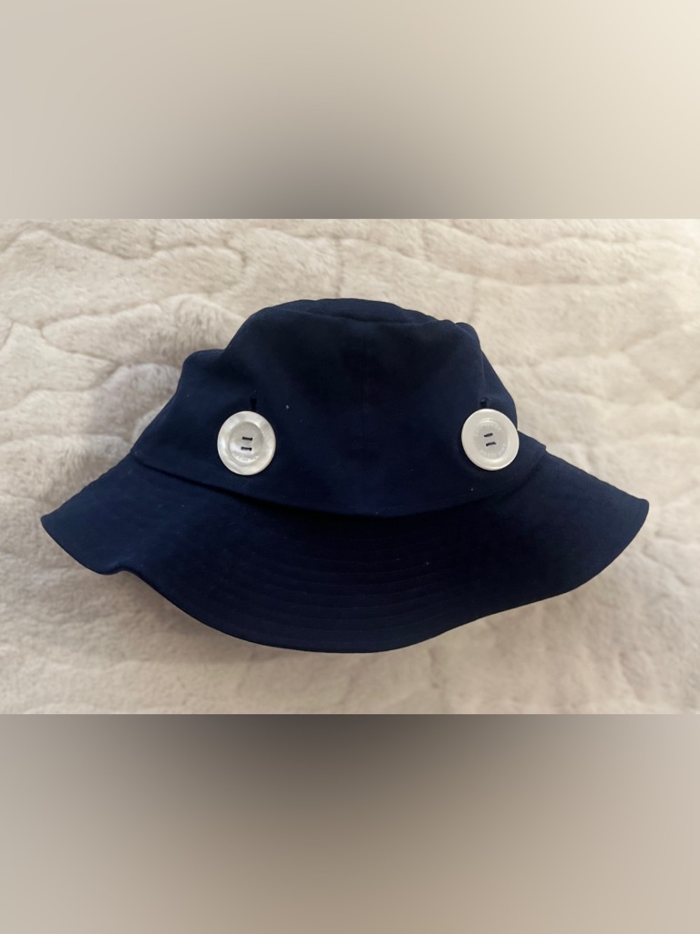 Kate Spade navy blue bucket hat with prominent white buttons.